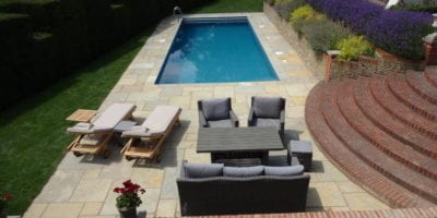 Simple outdoor swimmming pool with paving and furntiure