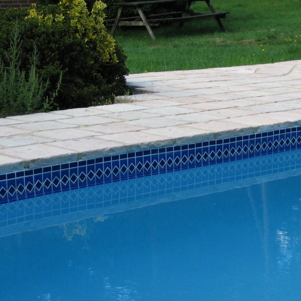Simple tiled swimming pool with rustic paving