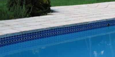Simple tiled swimming pool with rustic paving