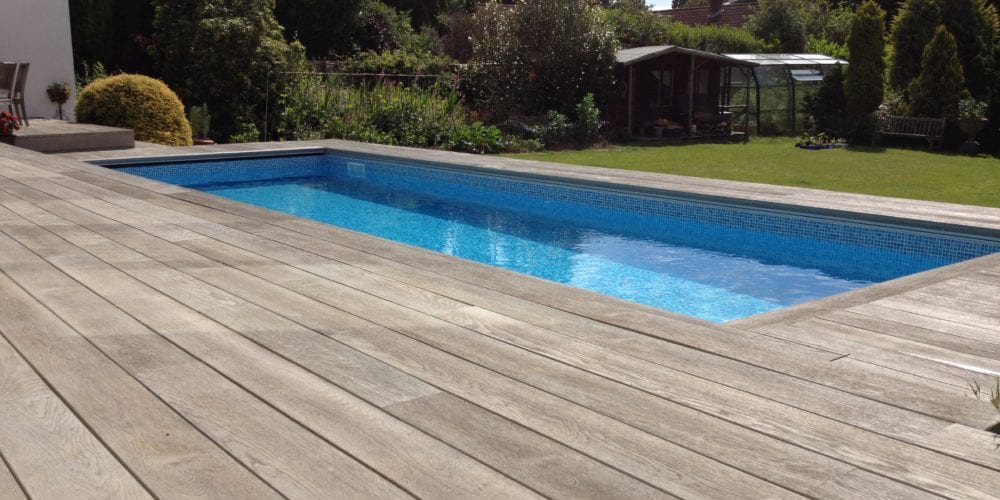 Modern wood panel surround on outdoor swimming pool with mosaic tile