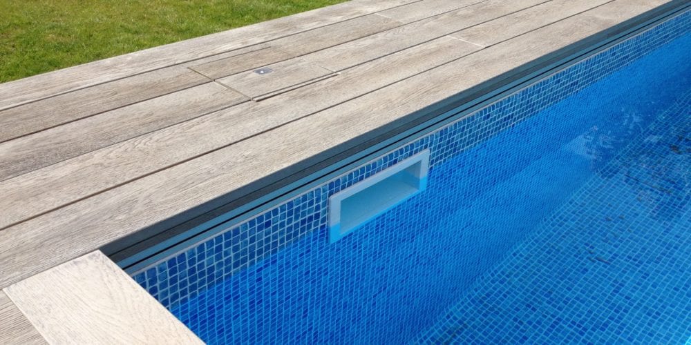 Modern wood panel surround on outdoor swimming pool with mosaic tile