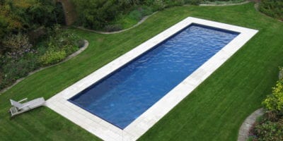 Swimming pool in lawn with white paving