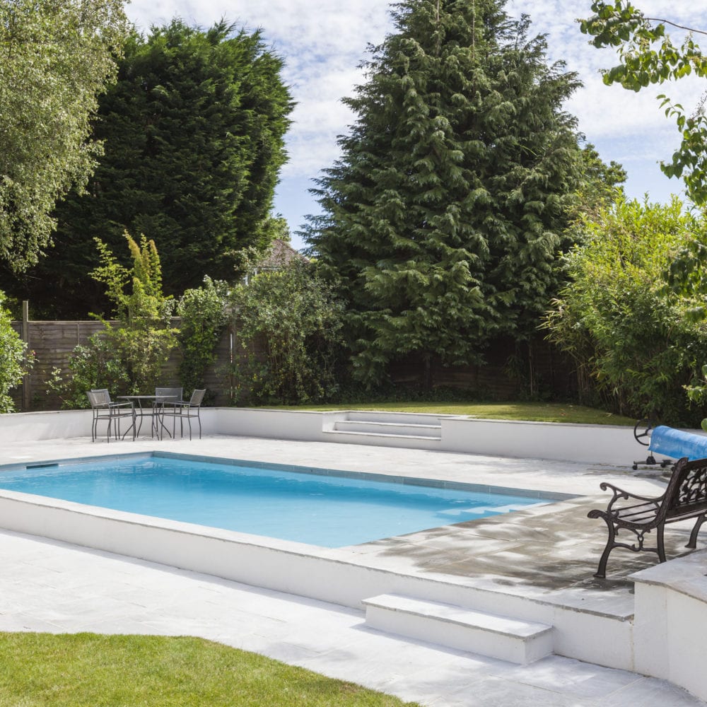 Outdoor pool in back garden with simple paving and steps